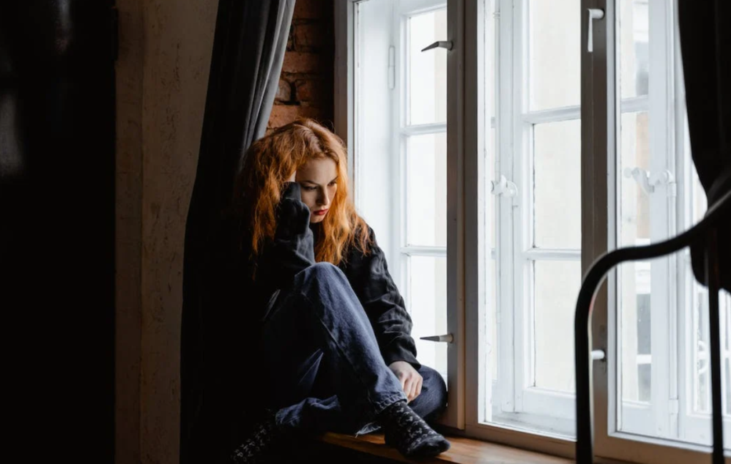 γυναίκα στο παράθυρο, κρατάει το κεφάλι της