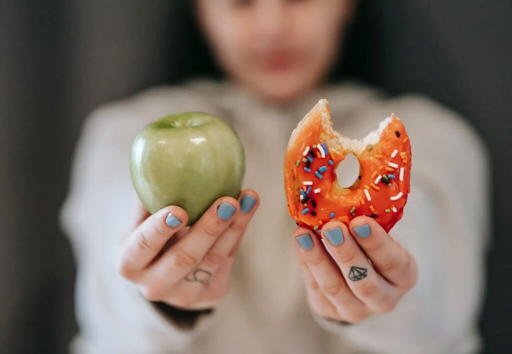 Γυναίκα κρατά μήλο και ντόνατ