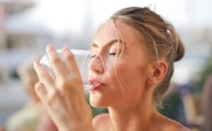 Νεαρή γυναίκα πίνει νερό από το ποτήρι