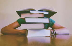 Νέος με πολλά βιβλία στο γραφείο του